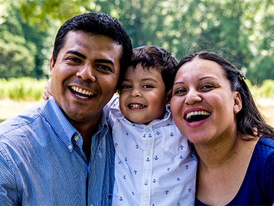Hispanic parents smiling and hugging son